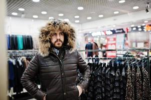 Stylish turkish man at the store of fur coats and leather jackets. Successful arabian beard man. photo