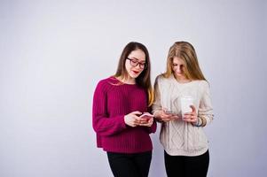 dos chicas con vestidos morados hablando o enviando mensajes de texto por teléfono en el estudio. foto