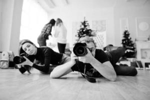 The team of two photographers lie on the floor and shooting on studio. photo