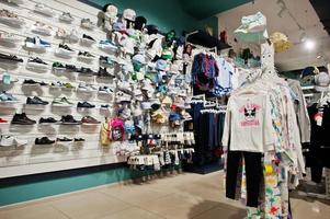 Luxury and fashionable brand new interior of kids shoes, caps and cloth store. photo