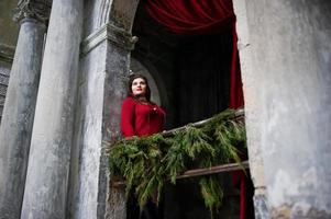 Brunette plus size model at red against arch with curtains. photo