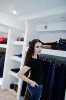 Brunette gorgeous girl in the clothing store boutique at casual clothes, black shirt and jeans. photo