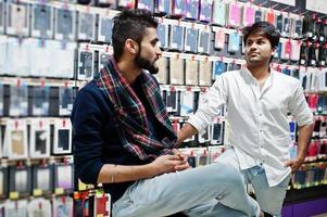 Two indian man customers buyer at mobile phone store choose a case for his smartphone. South asian peoples and technologies concept. Cellphone shop. photo