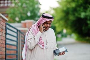 Middle Eastern arab business man posed on street against modern building with tablet and mobile phone at hands. photo