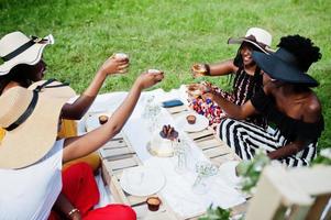 grupo de chicas afroamericanas celebrando la fiesta de cumpleaños y tintineando vasos al aire libre con decoración. foto