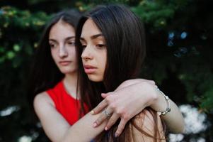 dos adolescentes vestidas de azul y rojo posaron al aire libre y abrazadas. foto