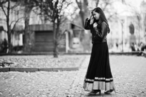 Pretty indian girl in black saree dress and leather jacket posed outdoor at autumn street. photo