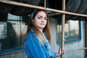 Young hipster girl in jeans jacket and head scarf at tire fitting zone. photo