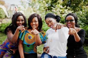 Group of four african american girls sitting outdoor and showing fingers. photo