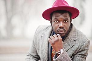 primer plano retrato de un elegante modelo afroamericano con abrigo gris, corbata de chaqueta y sombrero rojo. foto