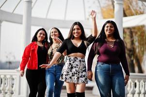 Group of four happy and pretty latino girls from Ecuador posed at street against ancient arch. photo