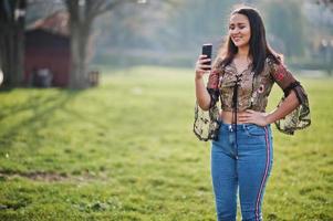 Bonita chica modelo latina de ecuador usa jeans posados en la calle con teléfono móvil. foto