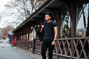 Handsome and fashionable indian man in black shirt with jacket posed outdoor. photo