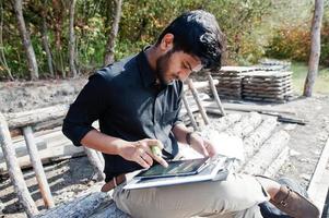 South asian agronomist farmer looking at diagram papers on farm. Agriculture production concept. photo