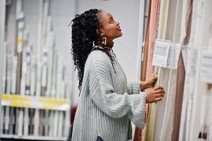 mujer africana eligiendo tul en el baño para su apartamento en una moderna tienda de muebles para el hogar. foto