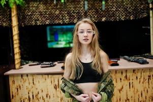 Military girl in camouflage uniform against army background on shooting range. photo