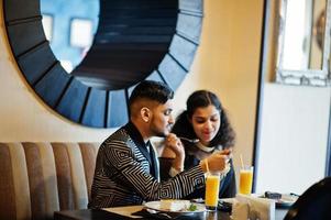 Lovely indian couple in love, wear at saree and elegant suit, posed on restaurant. photo