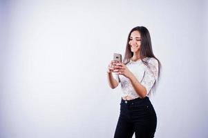 Portrait of a young beautiful woman in white top and black pants taking selfie. photo