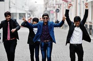 Group of 5 indian students in suits posed outdoor, having fun and dancing. photo