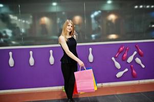 chica con bolsas de compras en el centro comercial contra la pared del club de bolos. foto