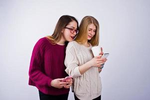 Two girls in purple dresses talking or texting on the phone in the studio. photo