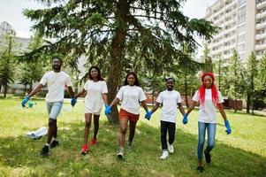 Group of happy african volunteers hold hands together in park. Africa volunteering, charity, people and ecology concept. photo