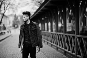 Handsome and fashionable indian man in black jeans jacket posed outdoor. photo