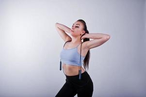 Cheerful attractive young fitness woman in top and black leggings with jump rope isolated over white background. photo