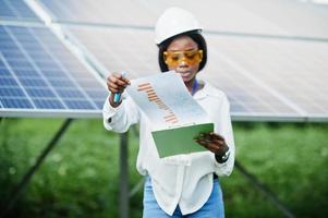 técnico afroamericano comprueba el mantenimiento de los paneles solares. ingeniera negra en la estación solar. foto