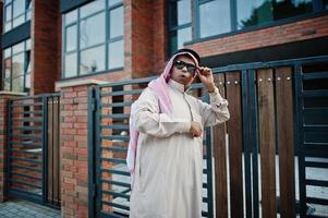 hombre de negocios árabe del medio oriente posó en la calle contra un edificio moderno con gafas de sol. foto