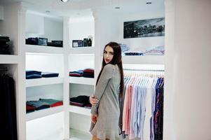 Brunette gorgeous girl in the clothing store boutique at gray dress. photo