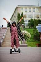 hermosa mujer afroamericana usando segway o hoverboard. chica negra en scooter eléctrico autoequilibrado de doble rueda. foto