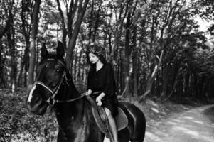 chica mística en ropa de corona en negro a caballo en madera. foto