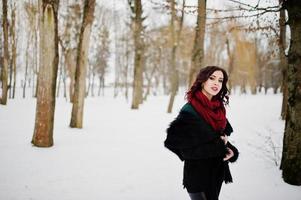 Brunette girl in green sweater, coat and red scarf outdoor on evening winter day. photo