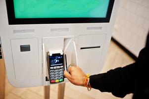 Hands of man customer at store place orders and pay by credit card through self pay floor kiosk for fast food, payment terminal. photo