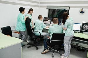 Medical theme.Observation room with a computer tomograph. The group of doctors meeting in the mri office at diagnostic center in hospital. Hold x-ray radiographic image. photo