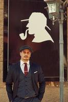 Portrait of retro 1920s english arabian business man wearing dark suit, tie and flat cap. photo