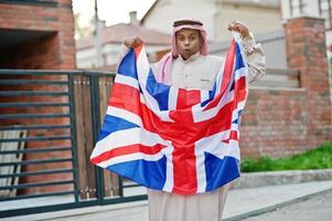 hombre árabe del medio oriente posó en la calle con la bandera de gran bretaña. concepto de inglaterra y países árabes. foto