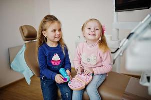 Two cutie little baby girls at dentist chair. Children dental. photo