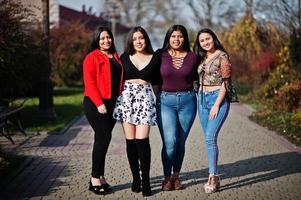 Group of four happy and pretty latino girls from Ecuador posed at street. photo