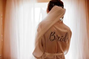 Wedding day preparation. Bride wearing a white bridal bathrobe. photo