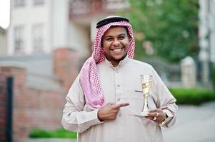 Middle Eastern arab business man posed on street with golden cup at hands. photo