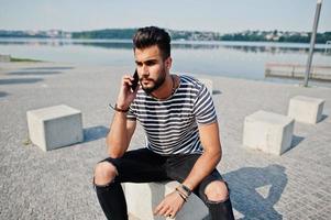 Handsome tall arabian beard man model at stripped shirt posed outdoor. Fashionable arab guy with mobile phone. photo