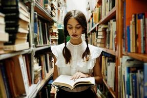 Girl with pigtails in white blouse at old library. photo