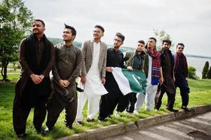 grupo de hombres paquistaníes vestidos con ropa tradicional salwar kameez o kurta con banderas de pakistán. foto