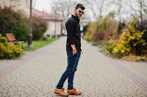 Indian stylish man at black shirt and sunglasses posed outdoor. photo