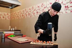 Professional chef wear in black making sushi and rolls in a restaurant kitchen of japanese traditional food. photo