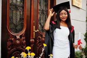 Young female african american student with diploma poses outdoors. photo