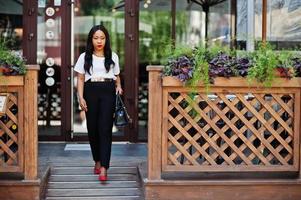 Stylish african american business woman with handbag on streets of city. photo