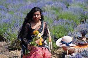 hermosa niña india usa vestido tradicional saree india en campo de lavanda púrpura. foto